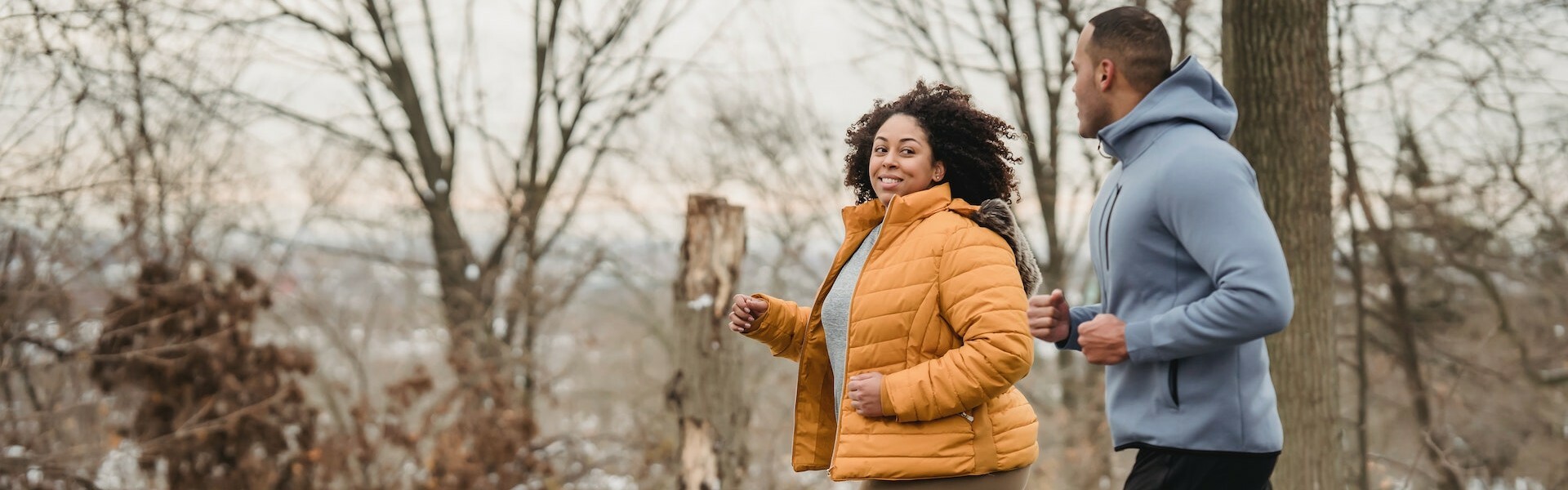 Hållbar träning - En kvinna och en man joggar i vinterlandskap.
